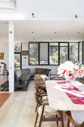 A modern living space with a dining area, large windows, and a view of the outdoors.