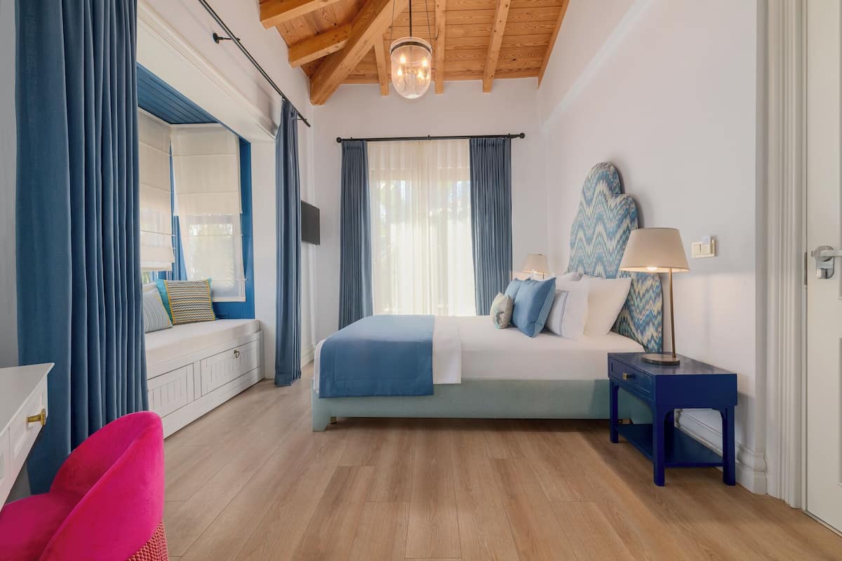 A bedroom with a bed, bedside table, lamp, and a window with curtains.