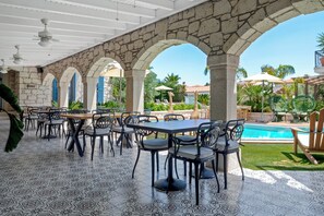 An outdoor dining area with stone arches, tables, and chairs. - Nefes Hotel Alacati (Cesme)