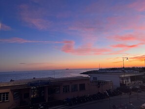 Vista costera con atardecer, edificios y motocicletas estacionadas.