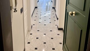 Un couloir doté d’un sol en marbre, de murs blancs et d’une porte verte.