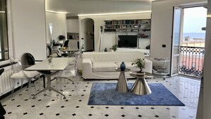 Une pièce moderne et bien éclairée, comprenant un coin repas, un canapé blanc et un balcon avec vue.