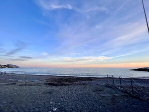 Una playa con cielo despejado, mar tranquilo y costa rocosa.
