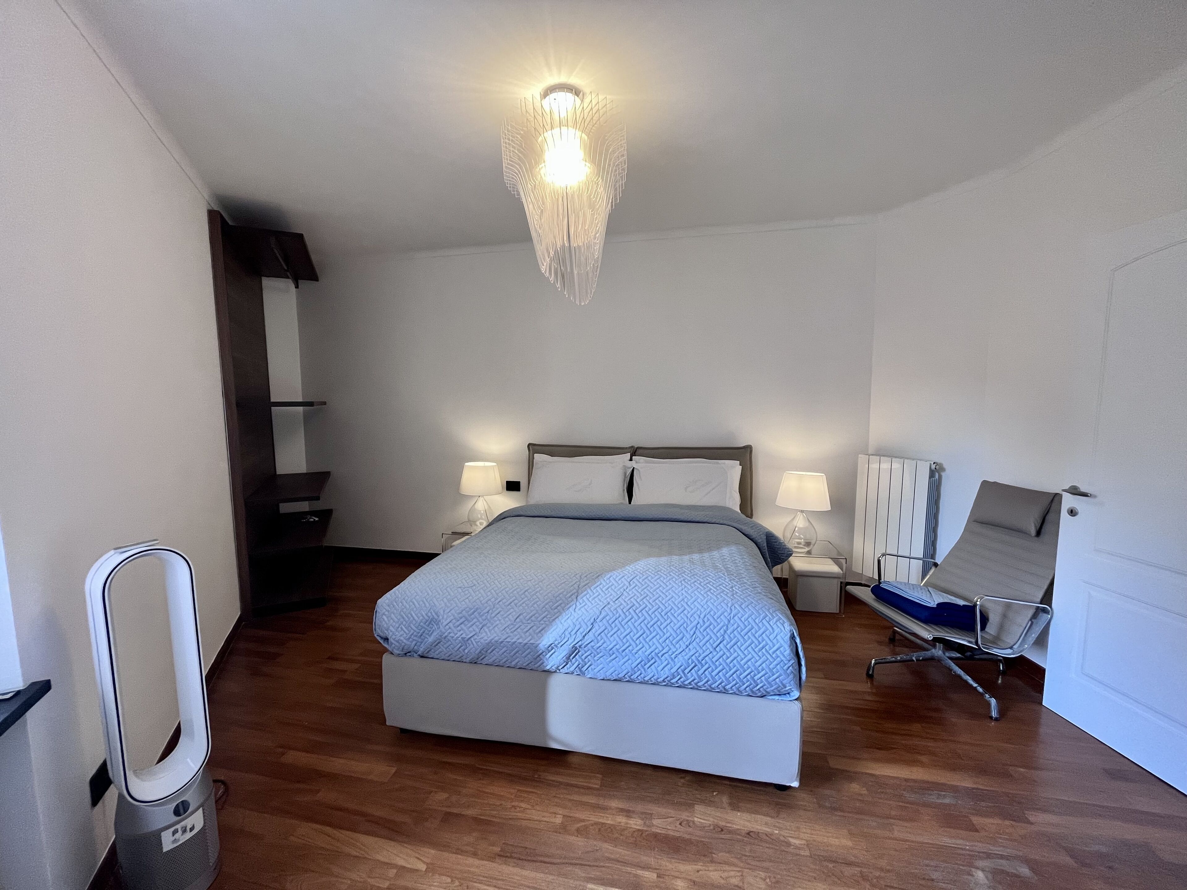 A modern hotel room with a large bed, bedside lamps, a desk, and a chair.