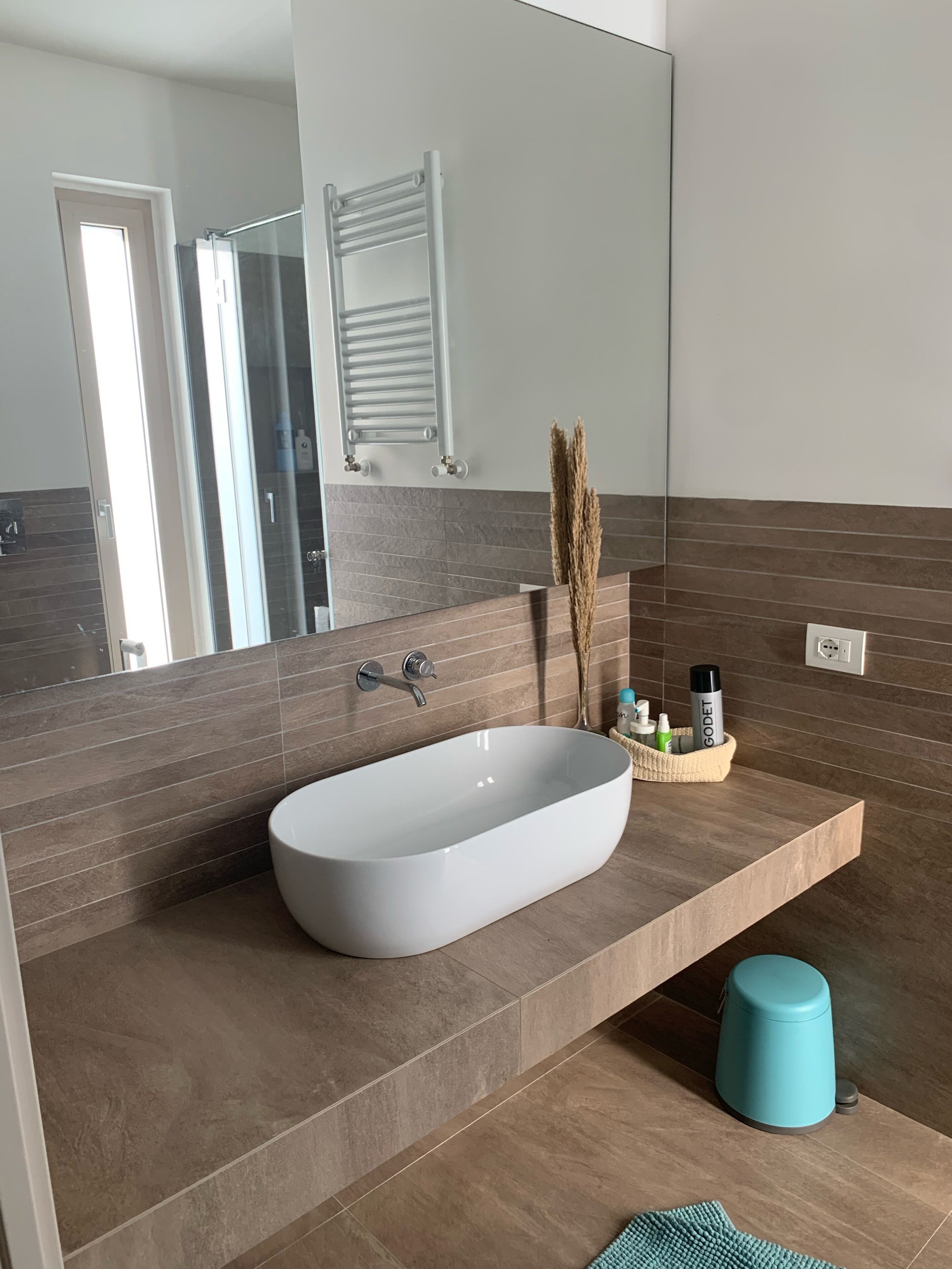Ein modernes Badezimmer mit einem großen Spiegel, einer weißen freistehenden Badewanne und einem Handtuchhalter.