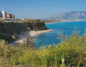 A coastal landscape with a beach, a cliff, and a building on the left. - Apartment in Villa with Jacuzzi (Balestrate)