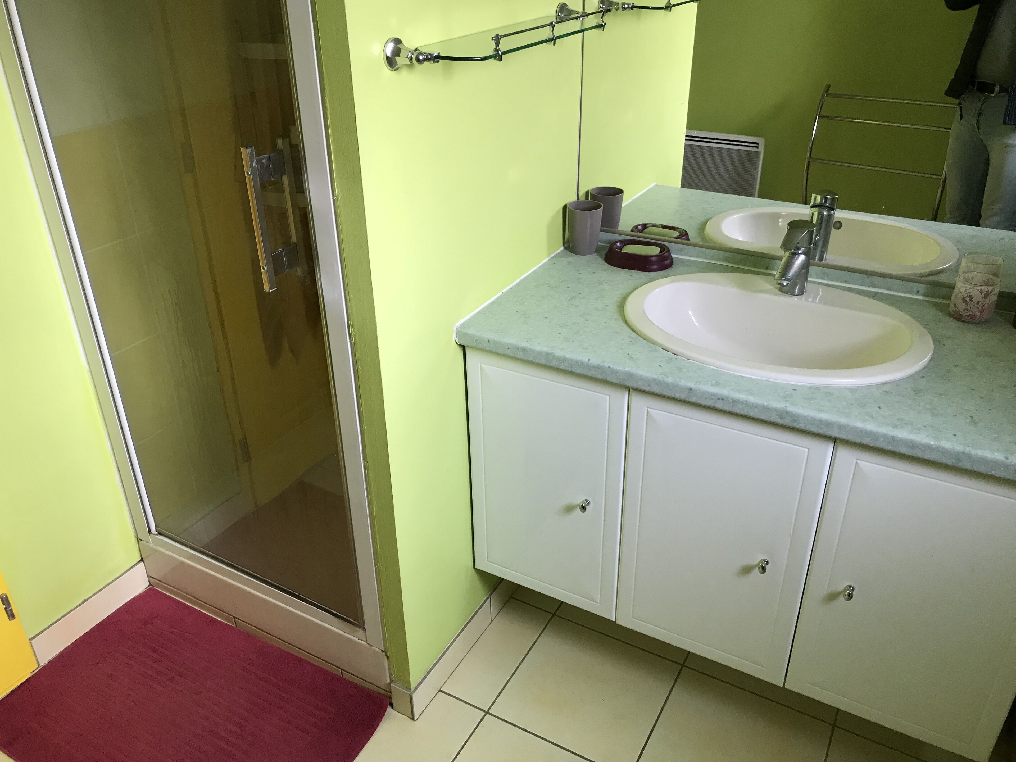 Une salle de bain avec une porte de douche en verre, un lavabo avec un miroir et des toilettes.