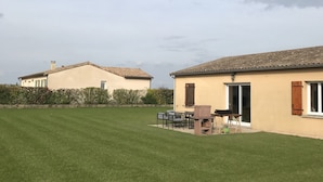A residential area with two houses, a well-maintained lawn, and a patio area with outdoor furniture. - Beautiful, quiet house for 4 to 6 people. 15mn Vallée des Singes - 25mn Futuroscope (Vivonne)