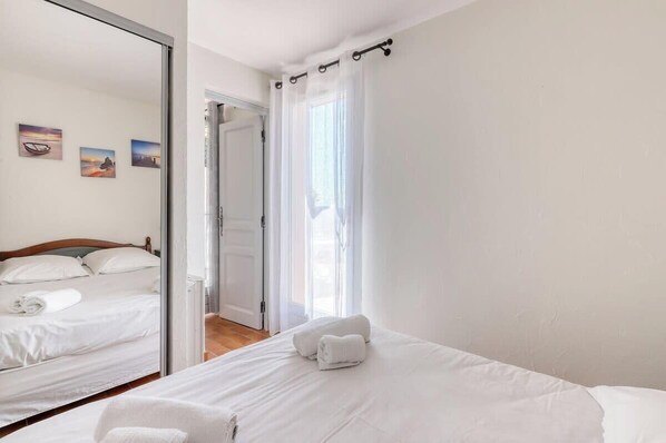 Una habitación de hotel con una cama, un espejo y una puerta que da a otra habitación.