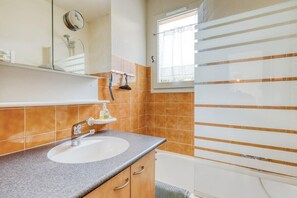 A bathroom with a sink, mirror, and shower.