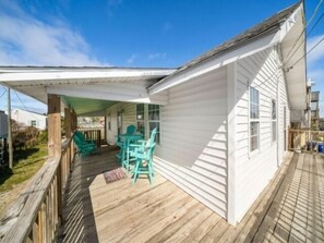 Eine überdachte Veranda mit Holzboden und türkisblauen Stühlen.