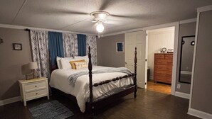 Une chambre à coucher avec un lit à baldaquin, une table de chevet, une commode et un ventilateur de plafond.