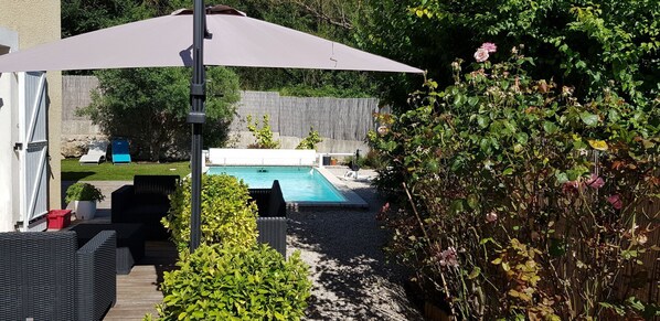 A backyard with a swimming pool, outdoor furniture, and a pergola.