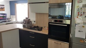 A compact kitchen with a stove, oven, and refrigerator, featuring a window and a wall-mounted Bosch dishwasher. - Villa in Provence well located, 90M2 with swimming pool (Auriol)