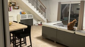 A modern living space with a staircase, a dining area, and a cat sitting by a window. - Villa in Provence well located, 90M2 with swimming pool (Auriol)