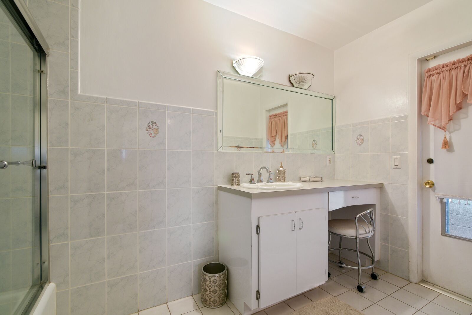 Un baño con ducha, un lavamanos con espejo y un perchero para toallas.