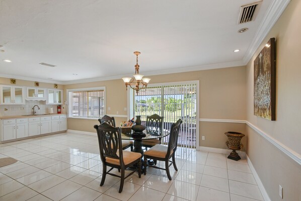 A spacious kitchen with white cabinets, a dining table with chairs, and a chandelier.