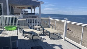 A deck with outdoor seating, a green trash bin, and a view of the beach. - Scituate oceanfront gem; 5BR  w/ wrap around deck. Perfect for family & friends (Scituate)