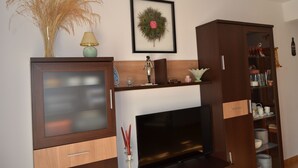 Ein Wohnzimmer mit Fernseher, Holzschrank und dekorativem Kranz an der Wand.