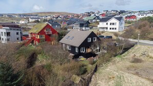 A residential area with houses, including a red house with a sloped roof and a black house with a gabled roof. - Lovely Apartments - 20 min walk from city centre (Tórshavn)