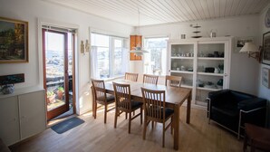 A dining area with a wooden table and chairs, a black sofa, and a cabinet with dishes. - Lovely Apartments - 20 min walk from city centre (Tórshavn)