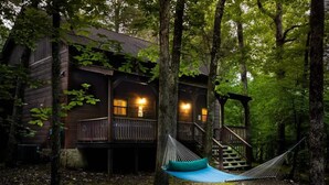 Eine Holzhütte mit Veranda und Geländer, voran hängt eine Hängematte.