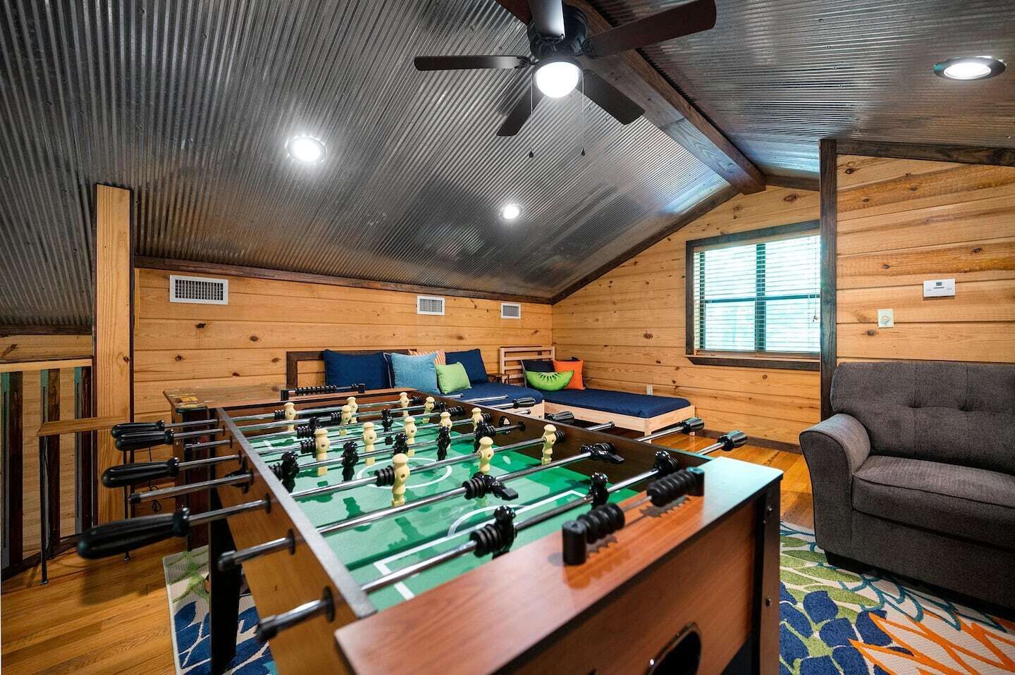 A cozy room with a foosball table, a sofa, and a bed with pillows.