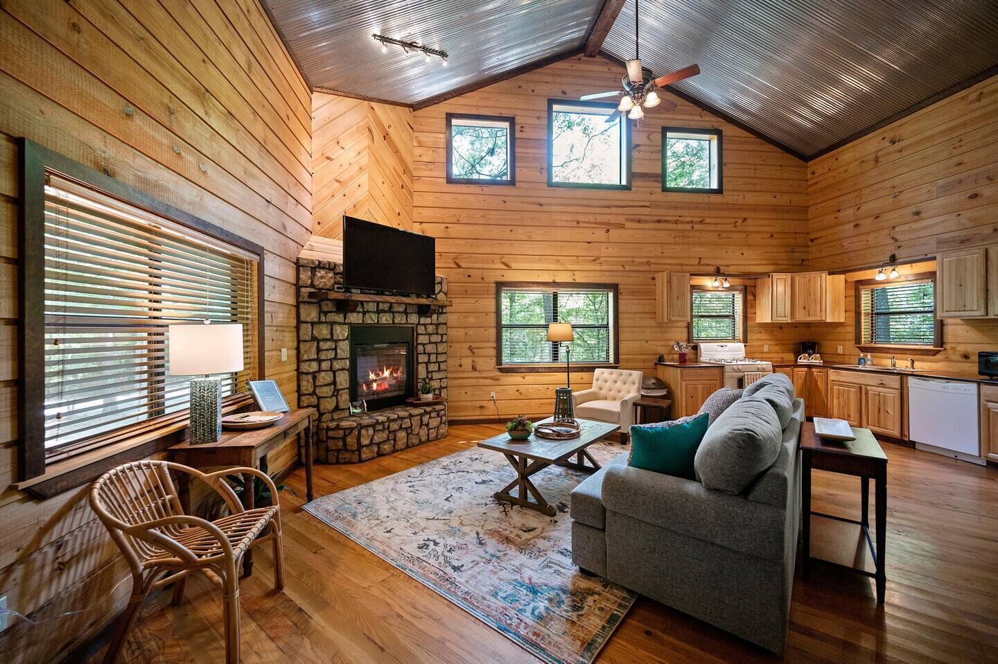 Ein gemütliches Blockhaus-Interieur mit Kamin aus Stein, Holzwänden, einer Essecke und einer Küche.