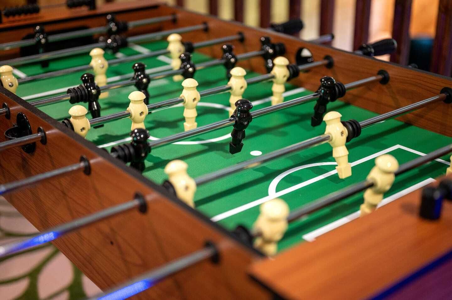 Primer plano de una mesa de fútbol de mesa con superficie verde y líneas blancas que delimitan el campo.