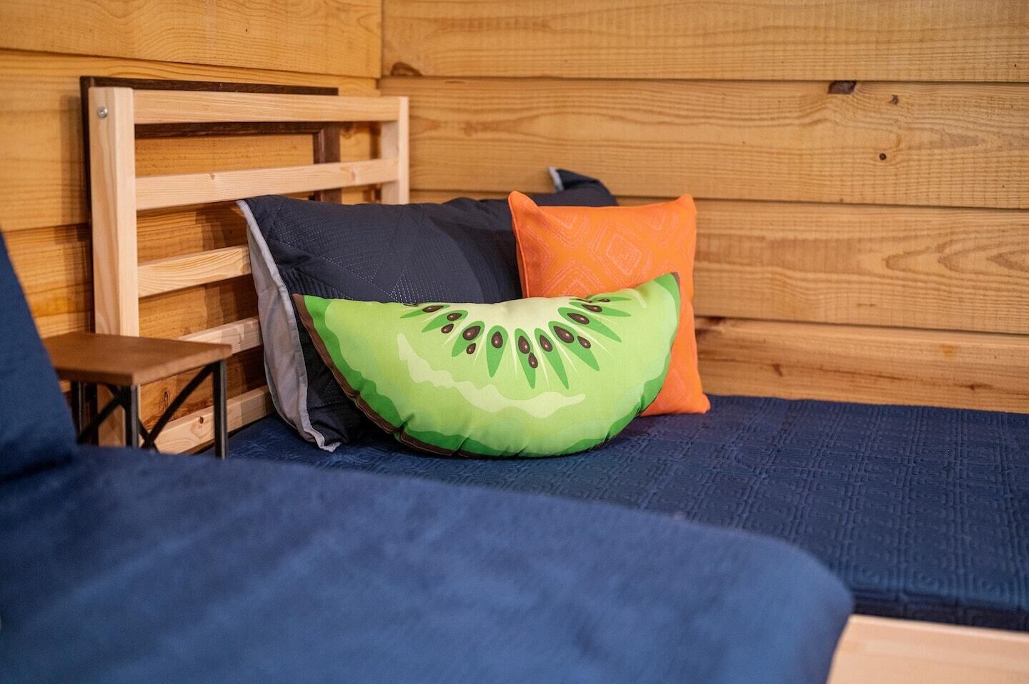 A wooden cabin interior with a bed, a small wooden table, and a bench.