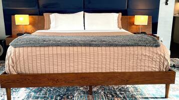 A bed with a wooden frame, two bedside lamps, a headboard, and a large rug.