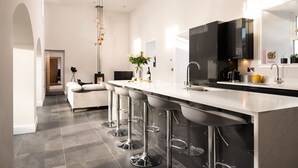 Una cocina moderna con una isla grande, taburetes de bar y un televisor de pantalla plana.