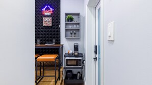A compact kitchen with a microwave, coffee maker, and a neon sign. - 5 mins to Coral Gables/ Parking/ Fast Wi-Fi/ Laundry (Miami)