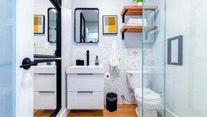 A modern bathroom with a glass shower enclosure, white cabinetry, a toilet, and a small plant on a shelf. - 5 mins to Coral Gables/ Parking/ Fast Wi-Fi/ Laundry (Miami)