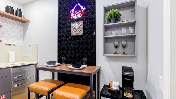 A modern kitchen with a neon sign, a coffee machine, and a shelf with glasses and a plant. - 5 mins to Coral Gables/ Parking/ Fast Wi-Fi/ Laundry (Miami)