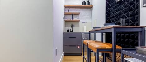 Une cuisine moderne avec des étagères en bois, un plan de travail et un coin repas équipé de tabourets.