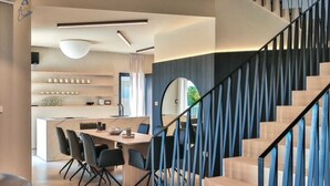 Un interior moderno con comedor, escalera y cocina.