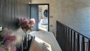 Un interior moderno con una pared de madera, una escalera y vistas a otra habitación.