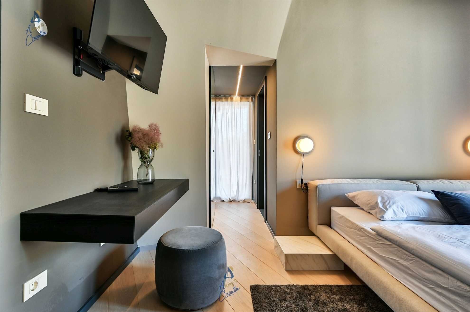 A modern bedroom with a bed, bedside table, and a wall-mounted TV.