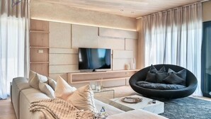 Una sala de estar moderna con un sofá, un sillón tipo bean bag negro, un televisor de pantalla plana y una mesa de centro.