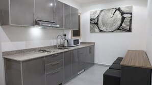 A modern kitchen with grey cabinets, a microwave, and a kettle. - BHomed (Salmiya)