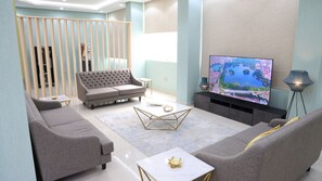 A modern living room with a grey sofa, a coffee table, and a flat-screen TV on a stand. - BHomed (Salmiya)
