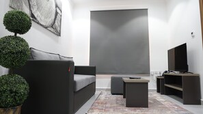 A modern living room with a grey sofa, a coffee table, and a flat-screen TV. - BHomed (Salmiya)