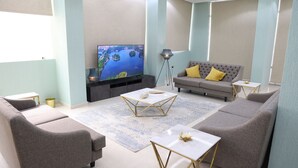 A modern living room with a flat-screen TV, grey sofas, a coffee table, and a patterned rug. - BHomed (Salmiya)