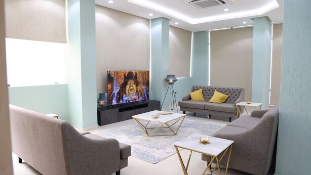A modern living room with a grey sofa, two armchairs, a coffee table, and a flat-screen TV on a stand. - BHomed (Salmiya)