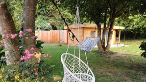 A white macrame chair hanging from a tree, a hammock, and a wooden structure in a garden. - Charming little house 5 minutes' walk from the beach (Locquirec)