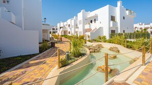 A resort with white buildings, a pool area, and a paved walkway. - Apartamento Babilonia (Mar de Pulpi) (San Juan de los terreros)