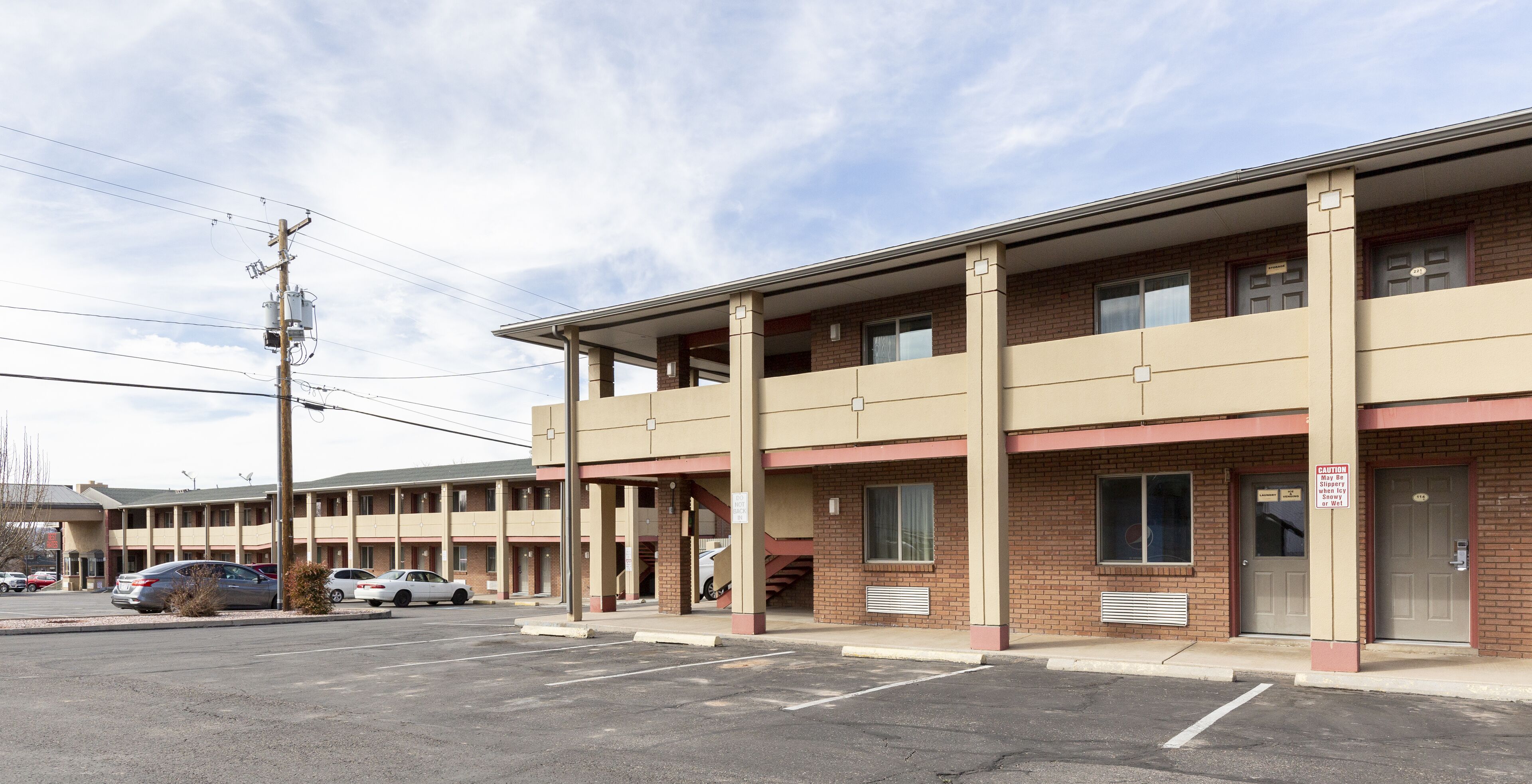 A multi-story motel with a parking lot in front.
