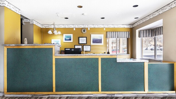 A reception desk with a check-out counter, framed pictures on the wall, and a window with a view of the outside.