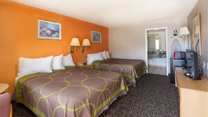 A hotel room with two beds, a desk with a computer, a TV, and a bathroom visible through an open door.